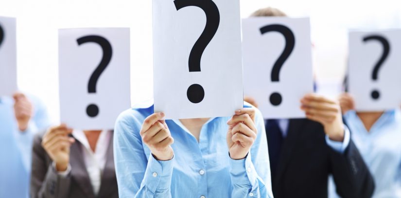 Colleagues holding question mark signs in front of their faces